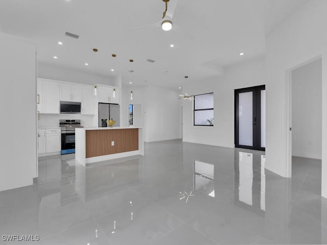 kitchen with a center island, hanging light fixtures, ceiling fan, stainless steel appliances, and white cabinets