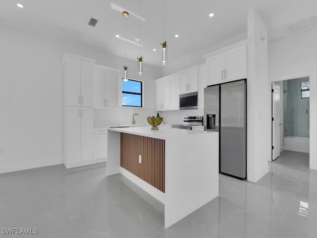 kitchen featuring stainless steel appliances, decorative light fixtures, a center island, and white cabinets