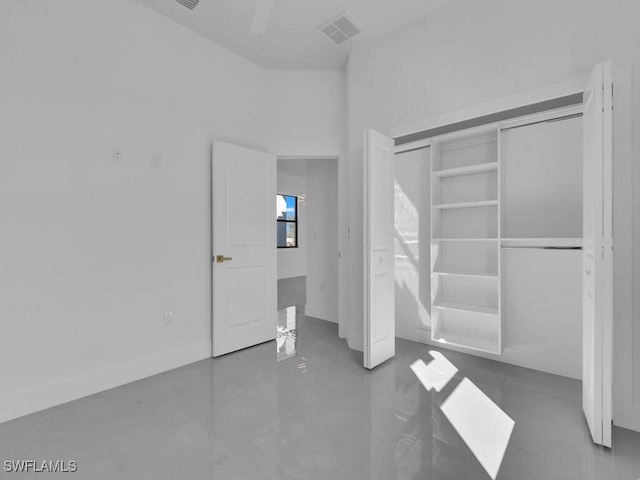 unfurnished bedroom featuring concrete flooring, a closet, and ceiling fan