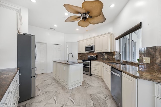 kitchen featuring white cabinetry, sink, tasteful backsplash, dark stone countertops, and appliances with stainless steel finishes