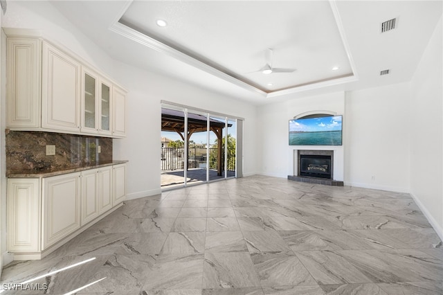 unfurnished living room featuring ceiling fan and a raised ceiling