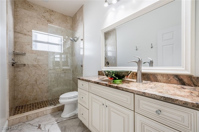 bathroom with a tile shower, vanity, and toilet