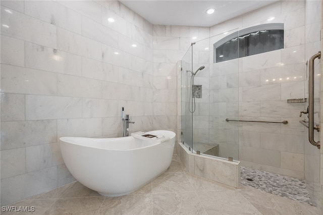 bathroom with tile patterned floors, separate shower and tub, and tile walls