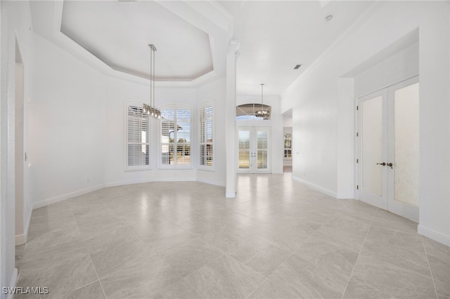 unfurnished living room with a chandelier, french doors, a tray ceiling, and ornamental molding