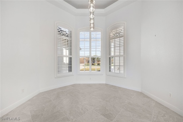 spare room featuring a tray ceiling and ornamental molding