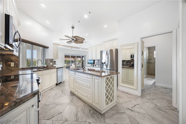 kitchen featuring dark stone counters, a center island with sink, sink, tasteful backsplash, and stainless steel appliances