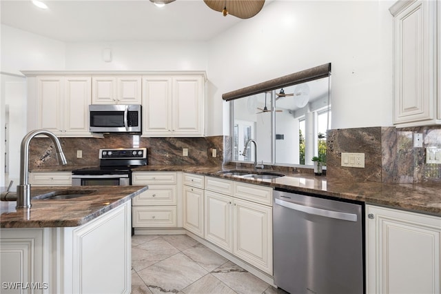 kitchen featuring stainless steel appliances, white cabinetry, dark stone counters, and sink