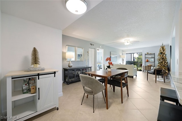 dining area with ceiling fan, light tile patterned floors, and a textured ceiling