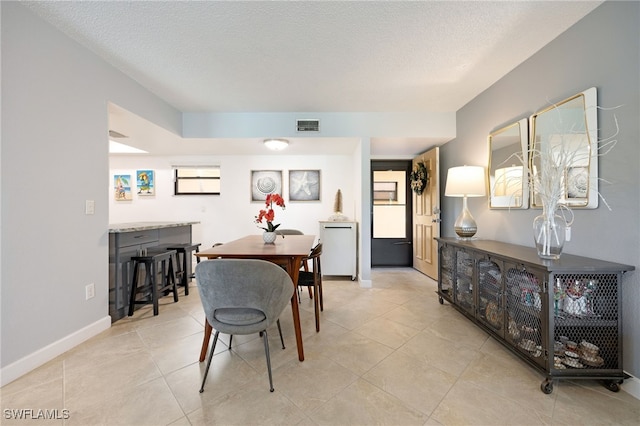 dining area with light tile patterned floors, a textured ceiling, and plenty of natural light