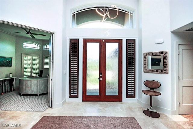 foyer entrance with french doors, a towering ceiling, a wealth of natural light, and ceiling fan