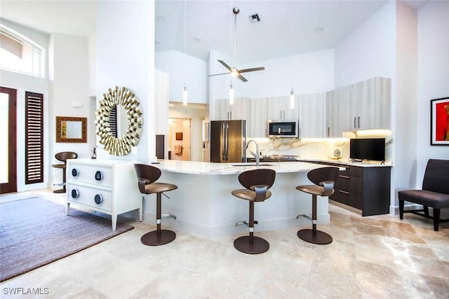 kitchen with a breakfast bar, a high ceiling, stainless steel appliances, and sink