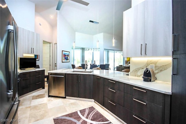 kitchen with sink, a high ceiling, stainless steel dishwasher, pendant lighting, and black refrigerator