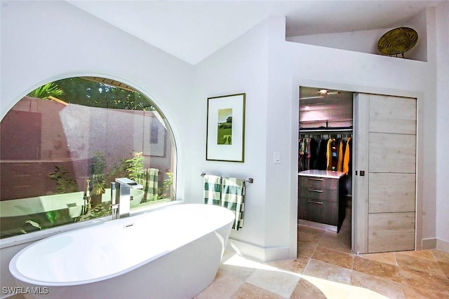 bathroom featuring a tub to relax in and vaulted ceiling