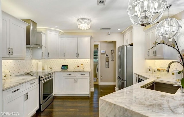 kitchen with white cabinets, sink, hanging light fixtures, wall chimney exhaust hood, and stainless steel appliances