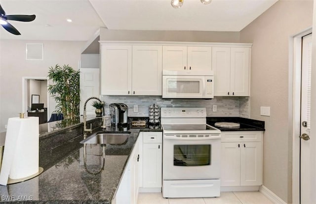 kitchen featuring sink, backsplash, dark stone counters, white appliances, and white cabinets