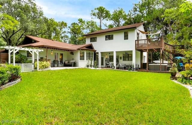 back of property with an outdoor hangout area, a deck, a patio area, a yard, and a hot tub