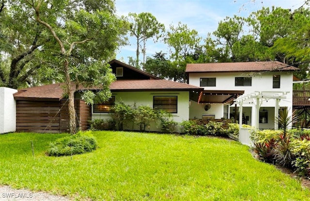 back of house with a pergola and a lawn