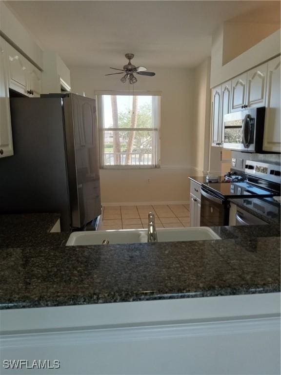 kitchen with dark stone countertops, appliances with stainless steel finishes, white cabinets, and a sink