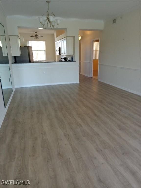 unfurnished living room featuring wood finished floors, visible vents, baseboards, crown molding, and ceiling fan with notable chandelier