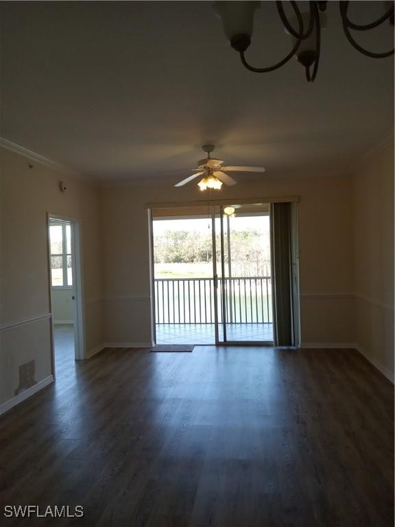 empty room featuring crown molding, wood finished floors, and baseboards