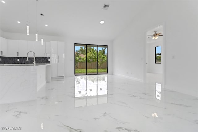 unfurnished living room featuring ceiling fan and plenty of natural light