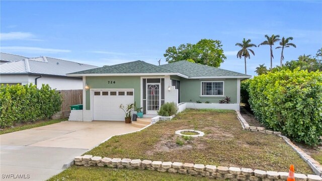 view of front of house with concrete driveway, roof with shingles, an attached garage, fence, and stucco siding