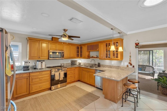 kitchen featuring light stone counters, appliances with stainless steel finishes, a kitchen breakfast bar, a peninsula, and a sink