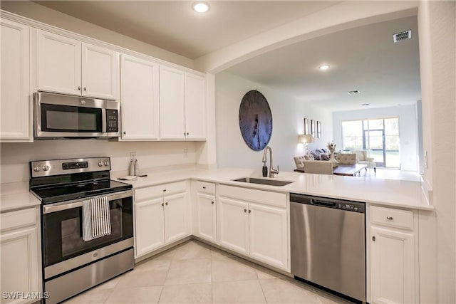 kitchen with visible vents, a sink, appliances with stainless steel finishes, a peninsula, and light tile patterned floors