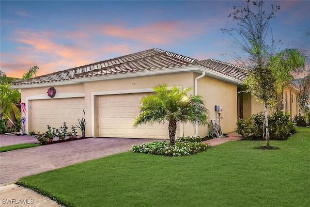 view of front of home featuring a yard, stucco siding, decorative driveway, and a garage