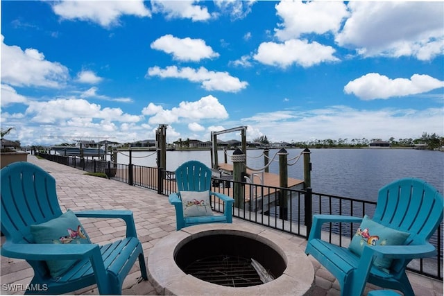 view of patio with a fire pit, a water view, and a dock