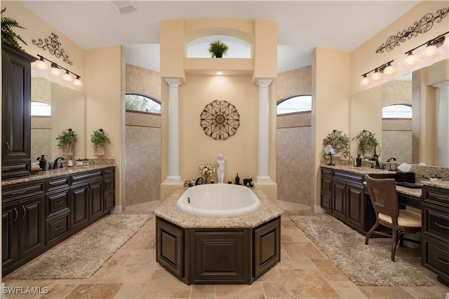 bathroom with a washtub, vanity, decorative columns, and plenty of natural light