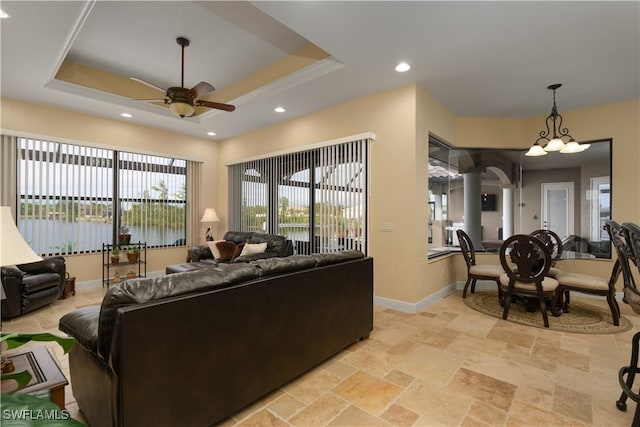 living room featuring a raised ceiling, ceiling fan, and a water view