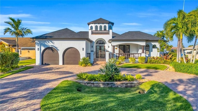 mediterranean / spanish home with a front lawn, covered porch, and a garage