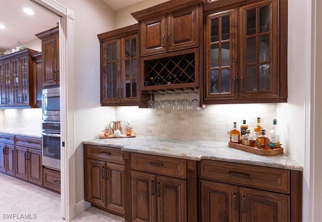 bar featuring tasteful backsplash, light stone countertops, and stainless steel appliances