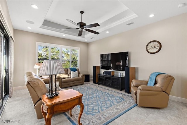 living room featuring a raised ceiling and ceiling fan