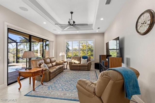 living room featuring light tile patterned floors, a tray ceiling, plenty of natural light, and ceiling fan