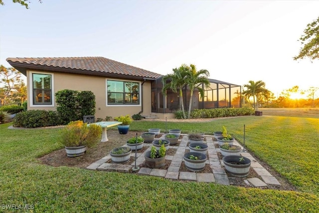 rear view of property featuring a lanai and a lawn