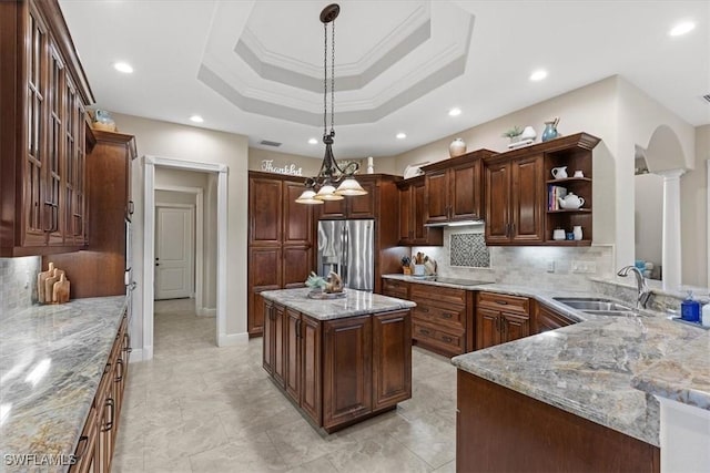 kitchen featuring sink, stainless steel refrigerator with ice dispenser, backsplash, decorative light fixtures, and a kitchen island