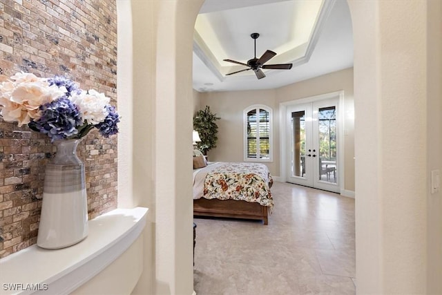 bedroom featuring access to outside, a tray ceiling, french doors, and brick wall