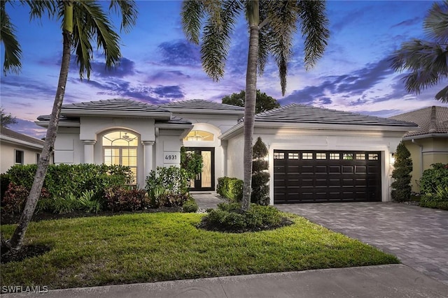 mediterranean / spanish-style home featuring a lawn and a garage