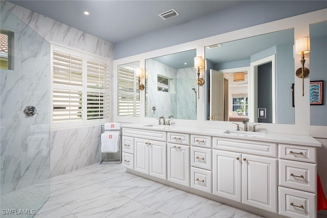 bathroom with vanity, a tile shower, and a wealth of natural light