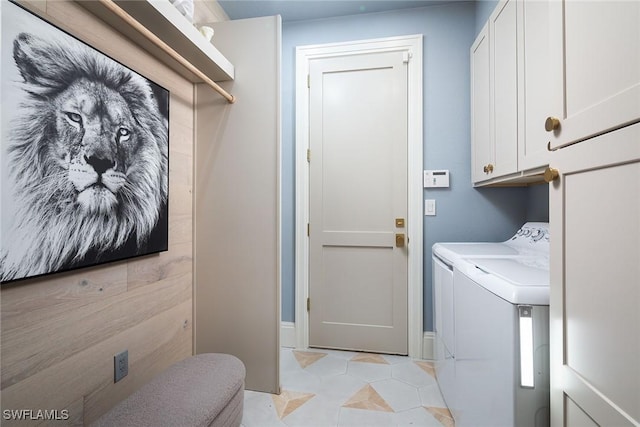 clothes washing area with cabinets, washing machine and dryer, and light tile patterned floors