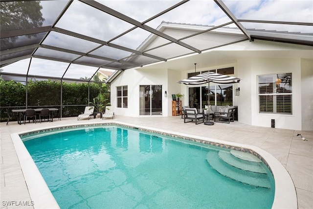 view of pool with a patio, an outdoor hangout area, and glass enclosure