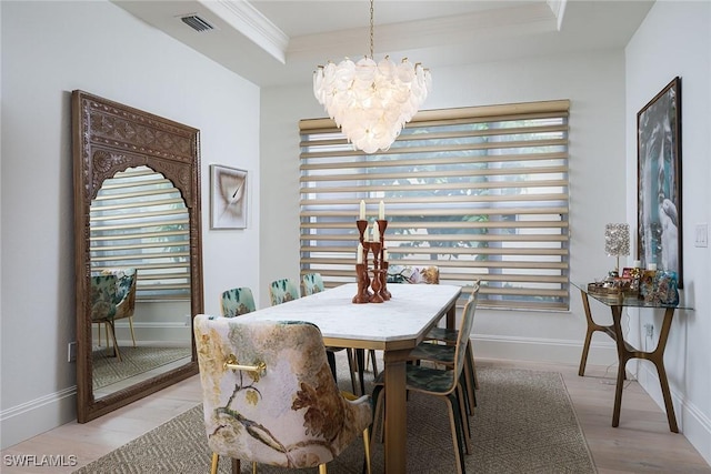 dining room featuring light hardwood / wood-style flooring, a raised ceiling, a wealth of natural light, and a notable chandelier