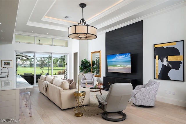 living room featuring crown molding, sink, a tray ceiling, and light wood-type flooring