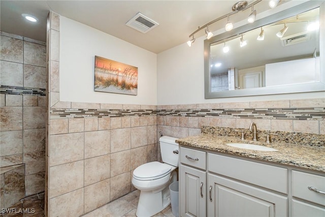 bathroom with tile walls, vanity, tile patterned flooring, and toilet