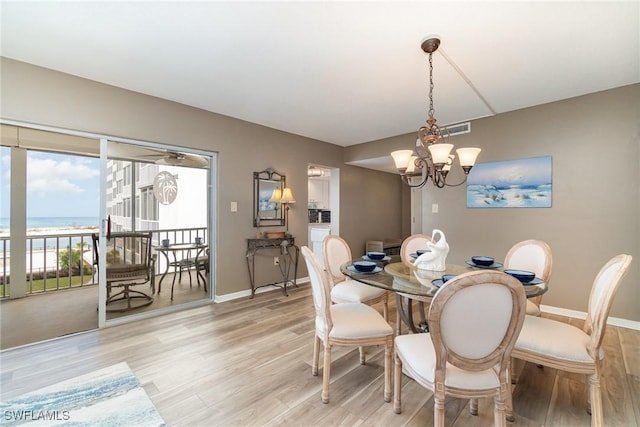 dining room with a water view, an inviting chandelier, and light wood-type flooring