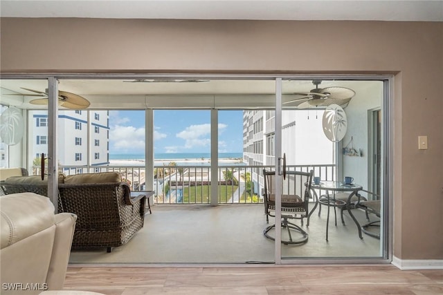 sunroom / solarium featuring a water view and ceiling fan