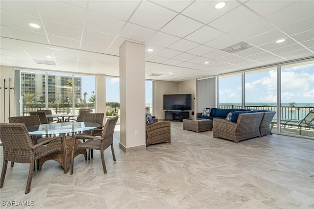 living room featuring plenty of natural light, floor to ceiling windows, and a paneled ceiling