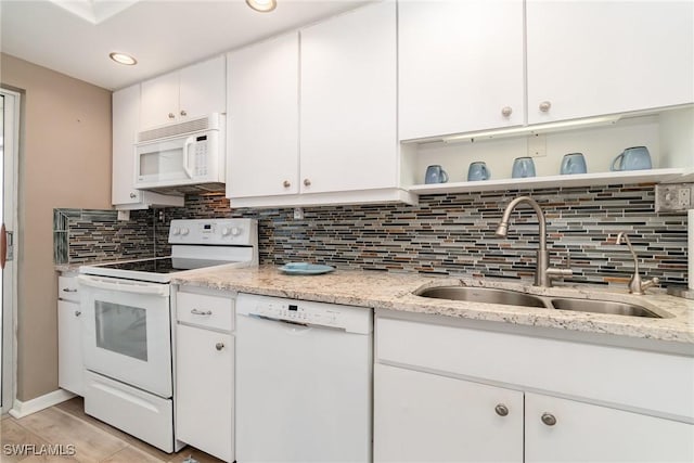 kitchen with sink, white appliances, light stone counters, white cabinets, and decorative backsplash